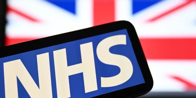 El logotipo del Servicio Nacional de Salud británico (NHS) aparece en una pantalla con la bandera del Reino Unido al fondo, el 7 de julio de 2024.
