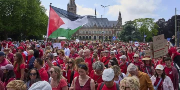 Decenas de miles de manifestantes vestidos de rojo marchan junto al Palacio de la Paz en La Haya durante una protesta contra la campaña de Israel en Gaza, el 15 de junio de 2025.