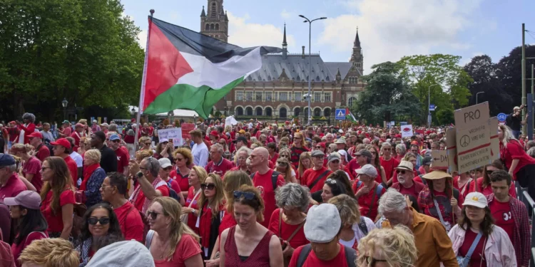 Decenas de miles de manifestantes vestidos de rojo marchan junto al Palacio de la Paz en La Haya durante una protesta contra la campaña de Israel en Gaza, el 15 de junio de 2025.