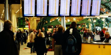 Pasajeros observan pantallas con vuelos retrasados y cancelados en el aeropuerto Schiphol de Ámsterdam.