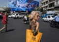 Peatones pasan junto a un cartel político en la plaza de la Revolución Islámica de Teherán