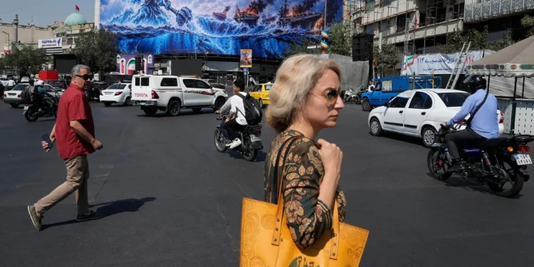 Peatones pasan junto a un cartel político en la plaza de la Revolución Islámica de Teherán
