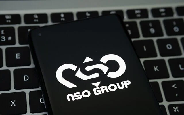 Logotipo de NSO Group en la pantalla de un teléfono sobre un teclado de computadora portátil