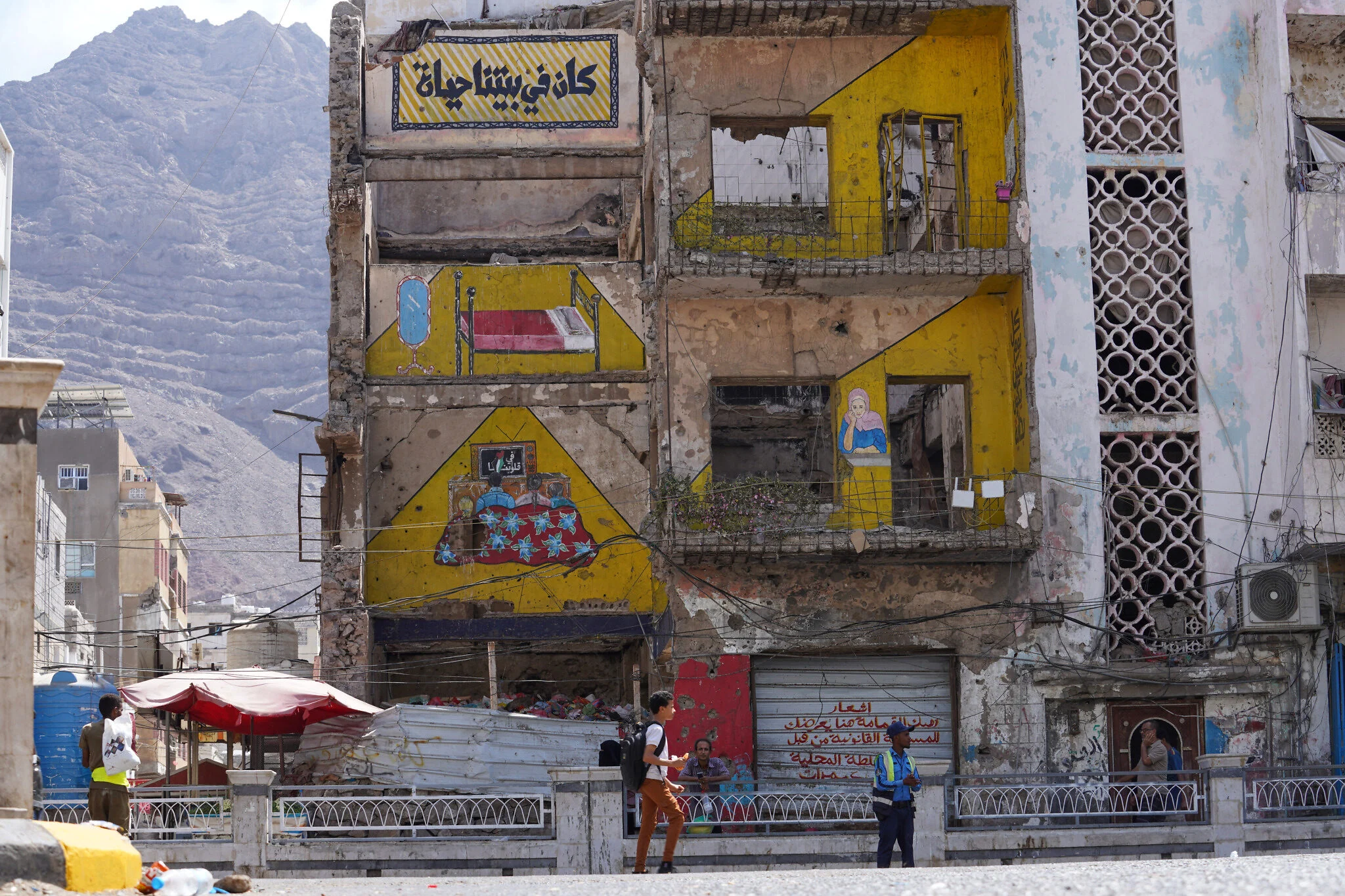 Edificio afectado por los combates en Adén Edificio dañado en Adén, Yemen, con una inscripción en árabe sobre la vida que hubo en el hogar