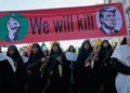 Mujeres vinculadas con la Guardia Revolucionaria iraní portan fusiles bajo una pancarta con Donald Trump en una mira y la frase «Lo mataremos», durante un desfile en Teherán el 18 de septiembre de 2026.