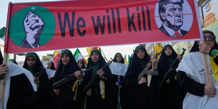 Mujeres vinculadas con la Guardia Revolucionaria iraní portan fusiles bajo una pancarta con Donald Trump en una mira y la frase «Lo mataremos», durante un desfile en Teherán el 18 de septiembre de 2026.