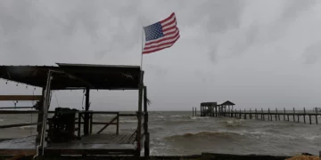 A US flag flaps in the wind generated by Hurricane Isaias on an empty beach on Mon Louis Island, Alabama, on October 9, 2026 (AP Photo/Octavio Jones)