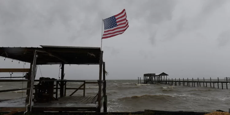 A US flag flaps in the wind generated by Hurricane Isaias on an empty beach on Mon Louis Island, Alabama, on October 9, 2026 (AP Photo/Octavio Jones)