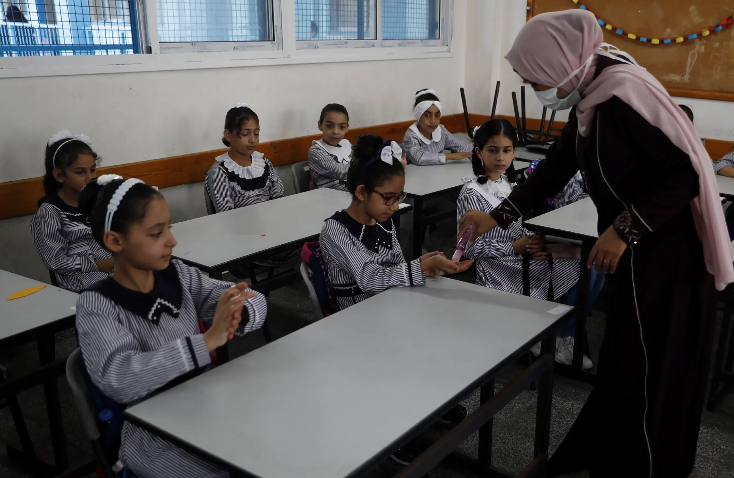 Una profesora de una escuela de UNRWA en la Franja de Gaza vierte desinfectante en las manos de alumnos durante la reapertura de las escuelas el 8 de agosto de 2020, tras meses de cierre por el coronavirus. Una profesora de una escuela de UNRWA en la Franja de Gaza vierte desinfectante en las manos de alumnos durante la reapertura de las escuelas el 8 de agosto de 2020, tras meses de cierre por el coronavirus.