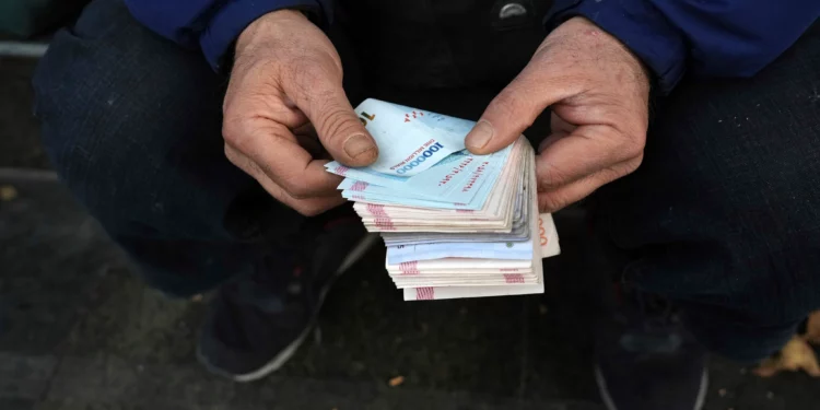 Un cambista callejero cuenta billetes iraníes en un distrito comercial del centro de Teherán, Irán, el 23 de diciembre de 2022, sin mostrar el rostro.