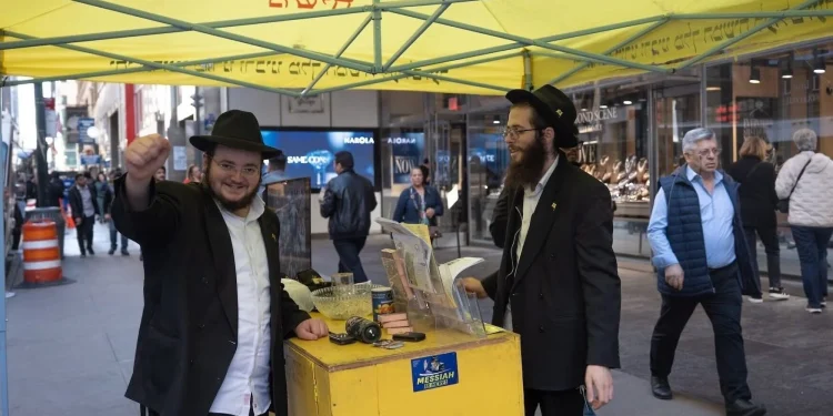 Shmuel Cohen (a la izquierda) hace una pausa en su labor de ayudar a transeúntes a colocarse tefilín en el Distrito de los Diamantes de Nueva York, el 23 de octubre de 2026.