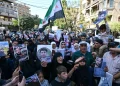 Sirios agitan banderas y muestran retratos de personas presuntamente detenidas durante incursiones militares israelíes en el sur de Siria, durante una protesta cerca del edificio de la ONU en Damasco el 23 de octubre de 2026.