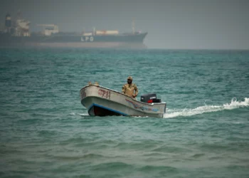 Un soldado yemení navega al norte del estrecho de Bab el-Mandeb, en Mokha, Yemen, con un buque cisterna de gas licuado de petróleo al fondo, 6 de abril de 2026.