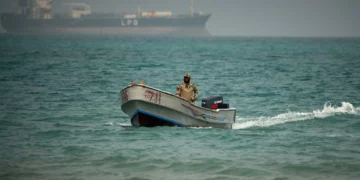 Un soldado yemení navega al norte del estrecho de Bab el-Mandeb, en Mokha, Yemen, con un buque cisterna de gas licuado de petróleo al fondo, 6 de abril de 2026.