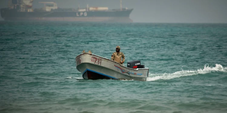 Un soldado yemení navega al norte del estrecho de Bab el-Mandeb, en Mokha, Yemen, con un buque cisterna de gas licuado de petróleo al fondo, 6 de abril de 2026.