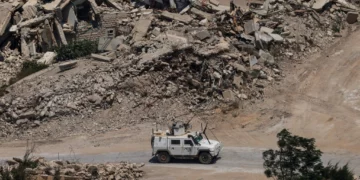 Un vehículo blindado de la Fuerza Provisional de las Naciones Unidas en el Líbano pasa junto a edificios destruidos en el sur del país el 22 de julio de 2026.