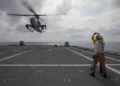 Marineros de la Armada de Estados Unidos señalan a un AH-1Z Viper del HMLA-367 durante su despegue desde la cubierta del USS Canberra en el mar de Filipinas.