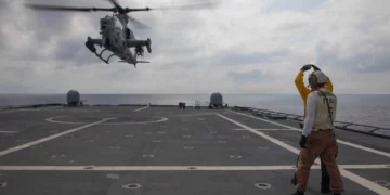 Marineros de la Armada de Estados Unidos señalan a un AH-1Z Viper del HMLA-367 durante su despegue desde la cubierta del USS Canberra en el mar de Filipinas.