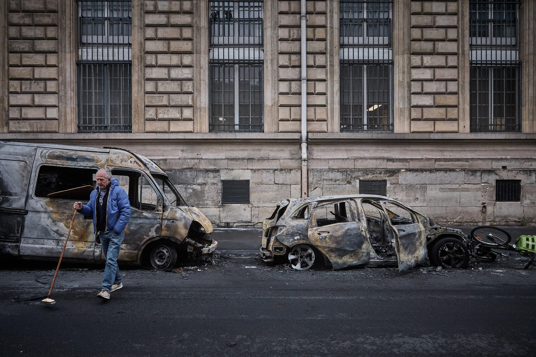 Un vecino cruza con una escoba la calle Yves Toudic de París tras un fin de semana de protestas.
